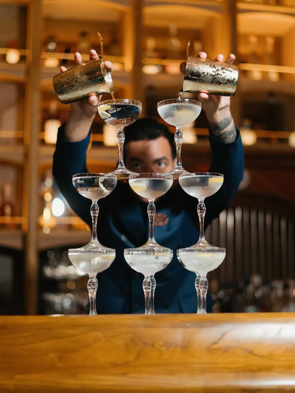 A Babylon bartender pouring a champagne tower