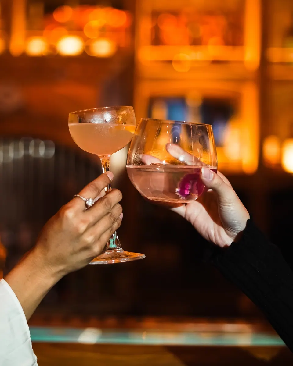 Two guests touching glasses at the bar at Babylon Garden Affair